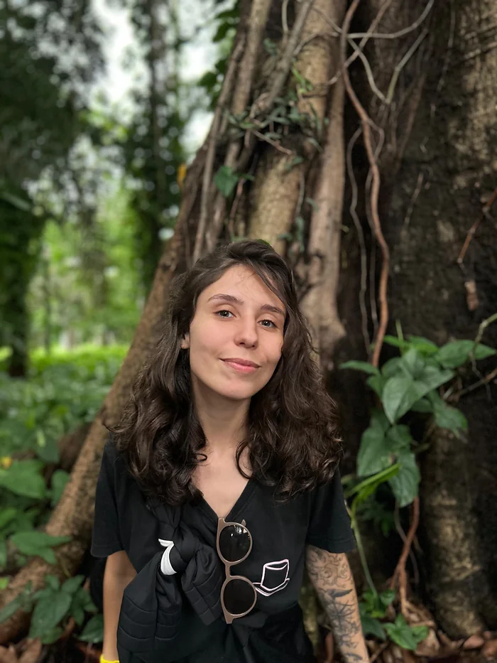 Karen junto ao tronco de uma árvore.